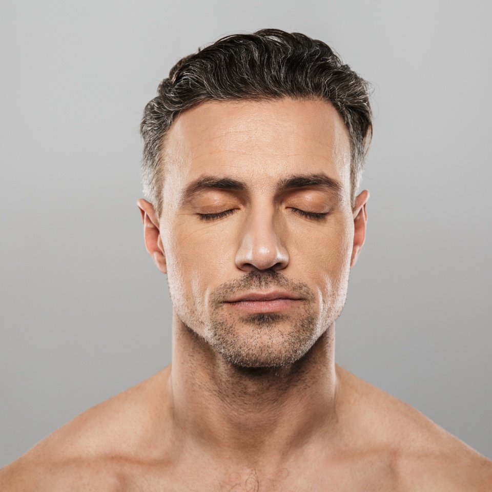 Image of handsome concentrated mature man standing isolated over grey wall background naked. Eyes closed.