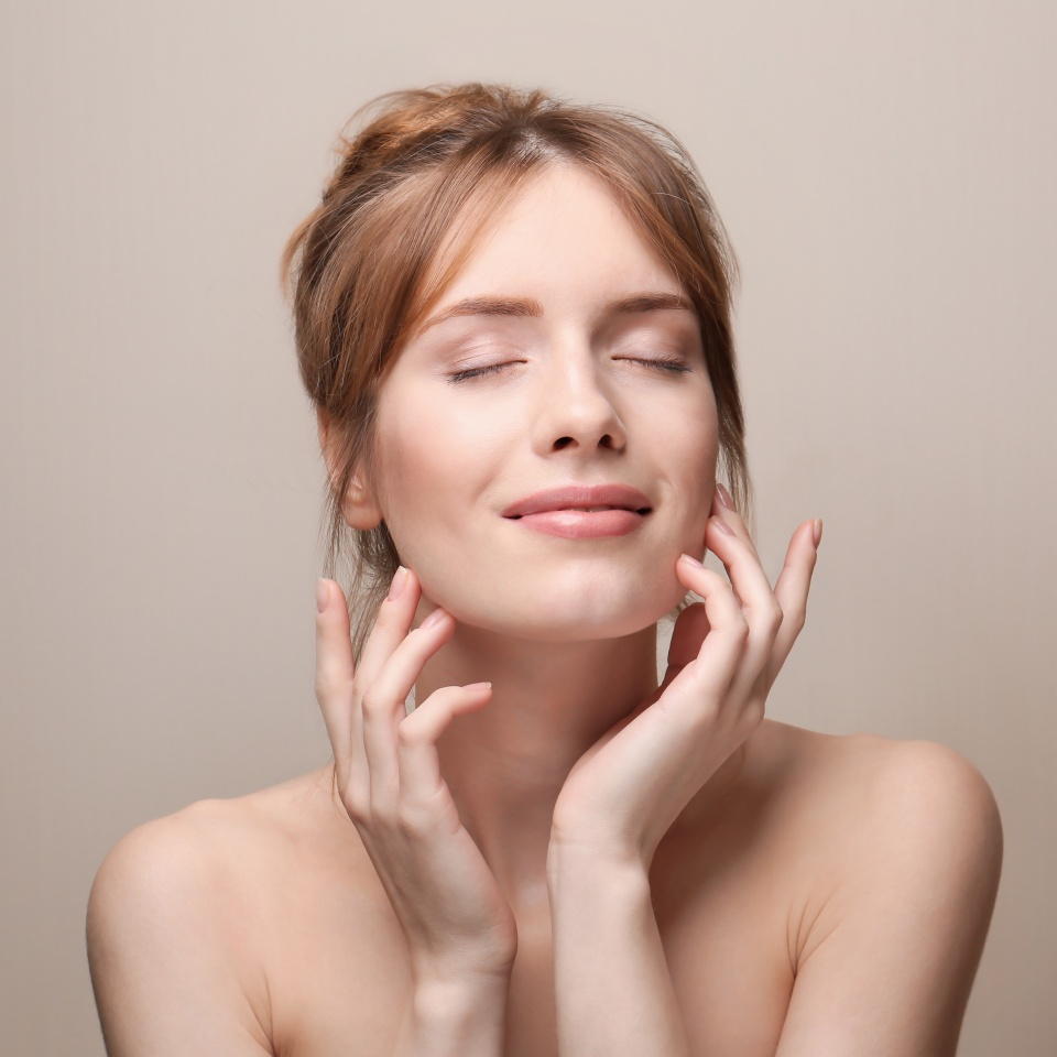 Beautiful young woman with silky skin on grey background