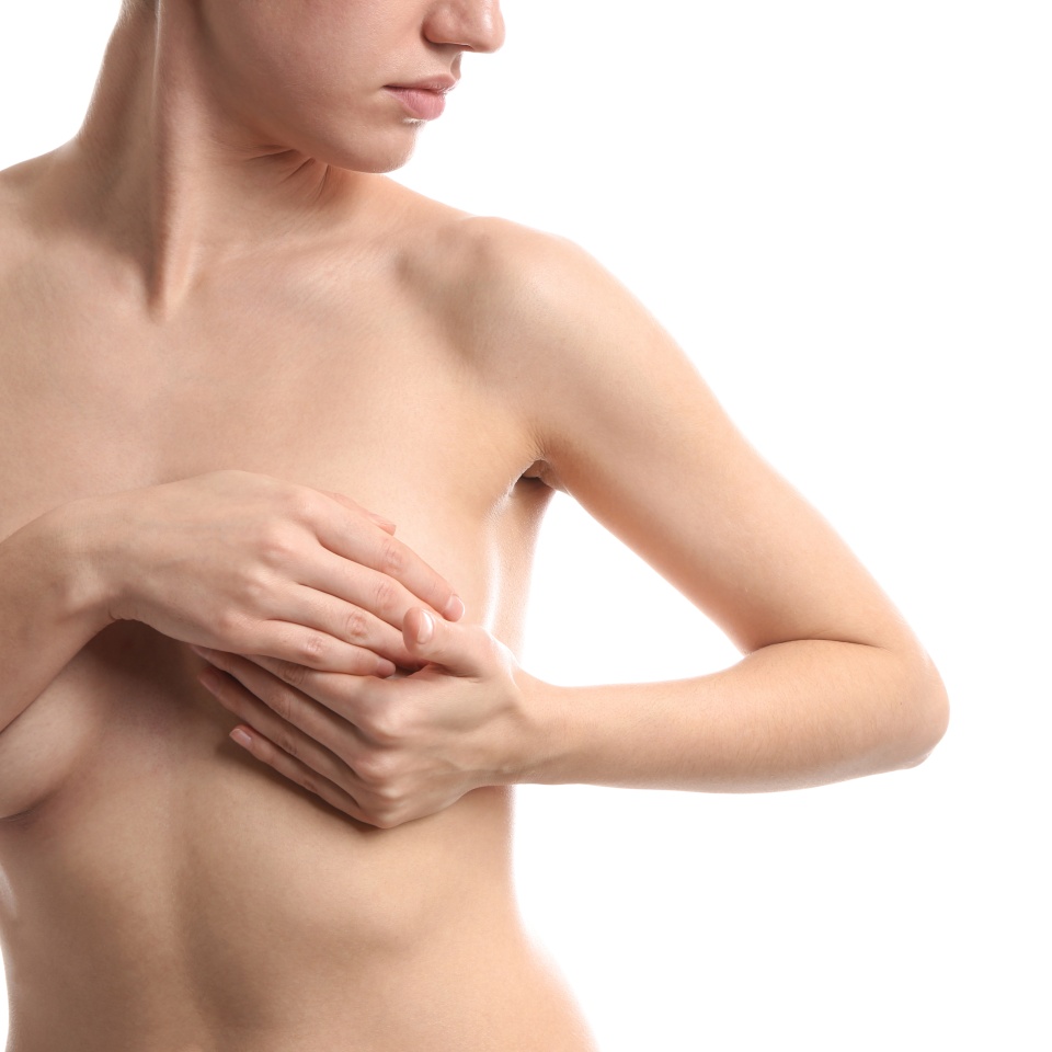 Young woman checking her breast on white background. Cancer awareness concept