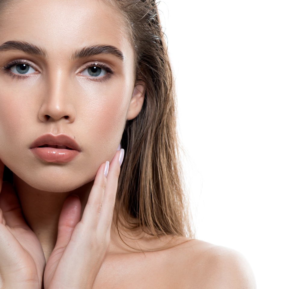 Beautiful young woman with clean perfect skin and wet glossy lips. Portrait of beauty model with natural make up, lifted brows and long eyelashes. Spa, skincare and wellness.