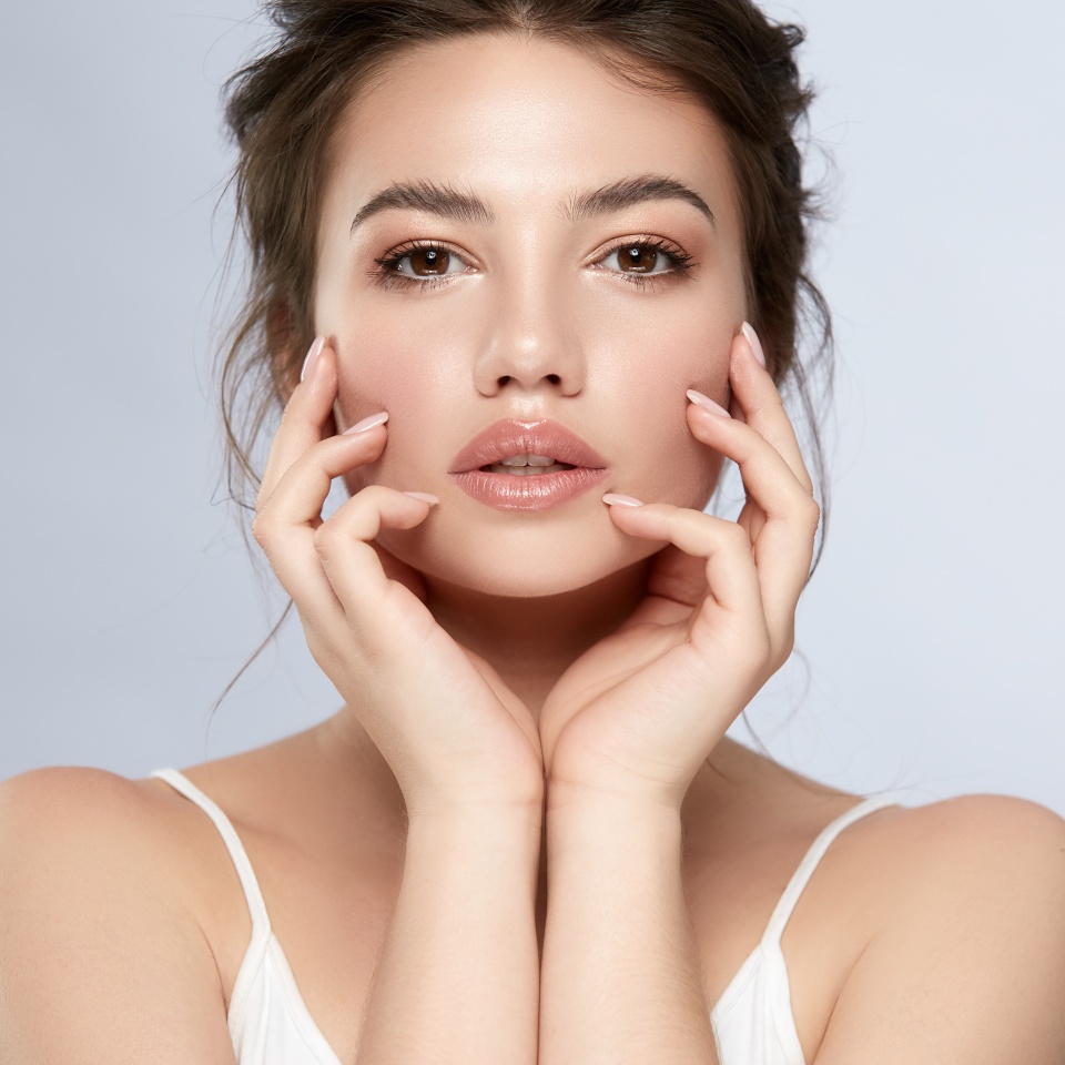 pretty woman touching face with arms and looking to camera, beauty portrait of female with perfect face and nude manicure