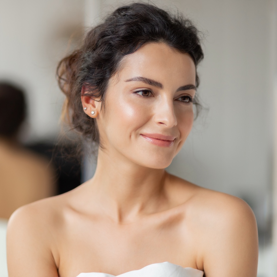 Portrait beautiful woman in bedroom. Headshot girl with natural beauty wrapped in blanket looking aside.