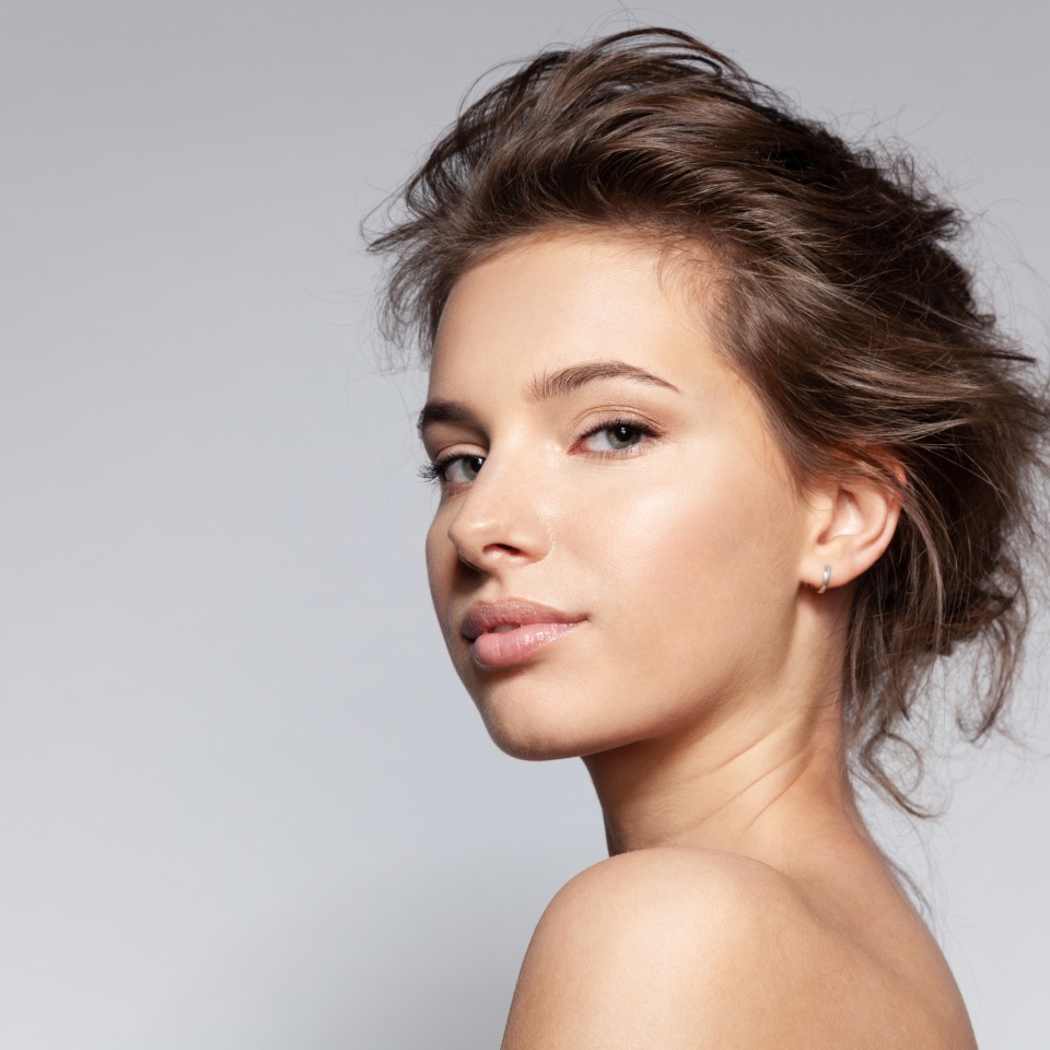 Portrait of beautiful young caucasian female with bare shoulder on gray background with copyspace for ad. Pretty millennial girl model with clean healthy moisturized skin. Natural beauty concept