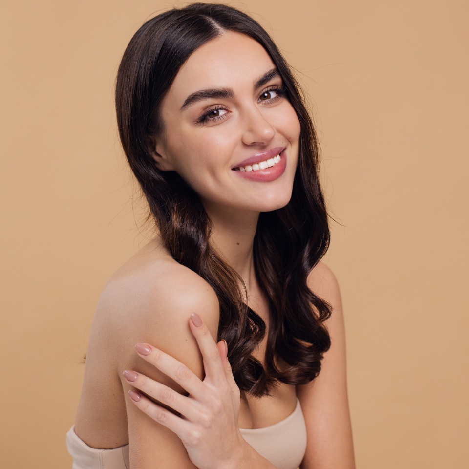 Beautiful young brunette woman with clean fresh skin on beige background, Face care, Facial treatment, Cosmetology, beauty and spa, female smiling portrait.