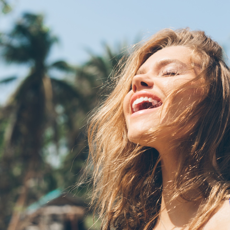 Beauty Sunshine Girl Portrait. Pretty happy woman enjoying summer outdoors. Sunny Summer Day under the Hot Sun on the Beach.