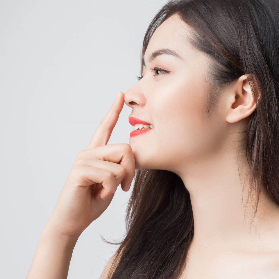 Young beautiful Asian woman with smiley face and red lips touching her nose.