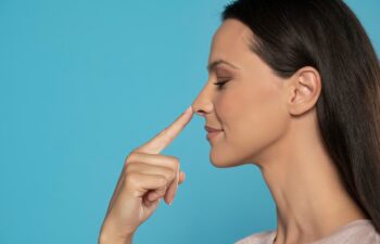 Profile of young woman touching her nose on a blue studio background
