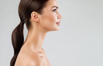 Beauty Model Perfect Face Profile. Brunette Woman with Healthy Smooth Facial Skin and Hair over White. Beautiful Girl Side view Portrait with Full Lips and Natural Make up. Female Plastic Surgery